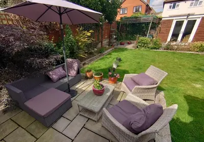 a patio with chairs and an umbrella in a yard at Rose Garden Retreat in Rayleigh