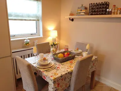 a dining room table with a basket of fruit on it at Rose Garden Retreat in Rayleigh