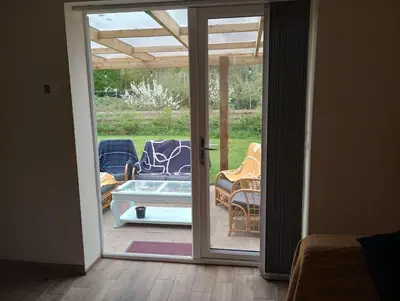 an open door to a patio with chairs and a table at The Walled Garden in Long Melford