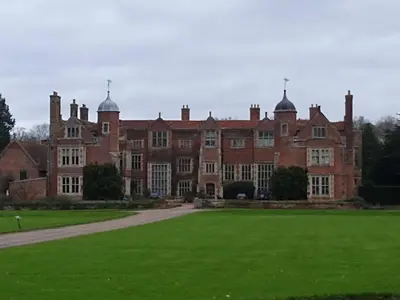 a large red brick building with a green lawn at The Walled Garden in Long Melford