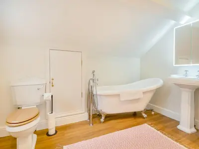 a bathroom with a tub and a toilet and a sink at Abbey Barn Farmhouse in Marham