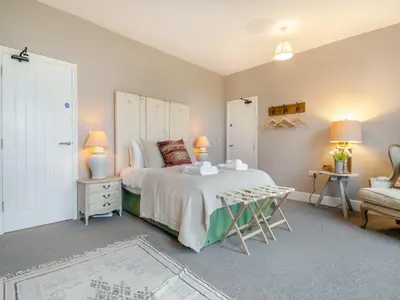 a bedroom with a bed and a table and a chair at Abbey Barn Farmhouse in Marham
