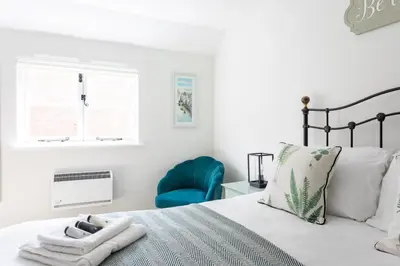 a bedroom with a bed and a blue chair at Maldon Executive Apartments in Maldon