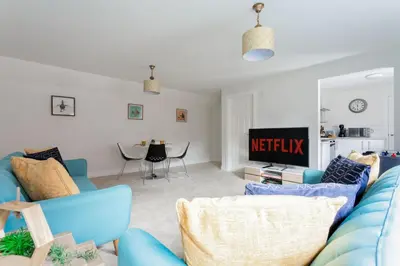 a living room with a blue couch and a tv at Maldon Executive Apartments in Maldon