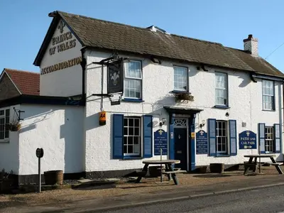 a white building with a picnic table in front of it at The Prince of Wales in Huntingdon