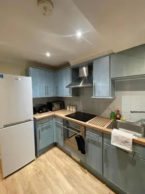a kitchen with blue cabinets and a white refrigerator at Relaxing double rooms in a beautiful house in Ipswich