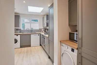 a kitchen with a sink and a washer and dryer at Elfleda Stay - Modern 5 bedroom house with parking in Cambridge