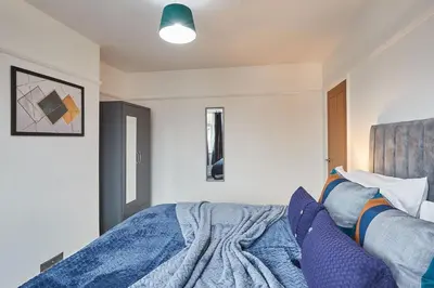 a bedroom with a bed with a blue comforter at Elfleda Stay - Modern 5 bedroom house with parking in Cambridge