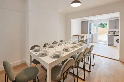 a white dining room with a table and chairs at Elfleda Stay - Modern 5 bedroom house with parking in Cambridge
