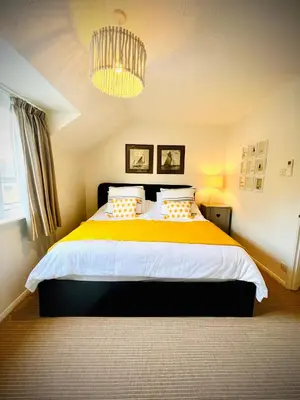 a bedroom with a large bed with a yellow blanket at Gorgeous Comfy Cottage Walking Birdwatching Paddle Boarding and Seafood on the Doorstep in West Mersea