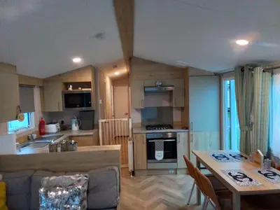 a kitchen and living room with a table and a dining room at PET FREE family mobile Home sleeps 8 with large secured decking Sea wick holiday park in Clacton-on-Sea