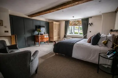 a bedroom with a bed and a chair and a desk at The Red Lion in East Bergholt