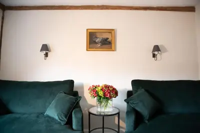 a living room with two green couches and a table with flowers at The Red Lion in East Bergholt