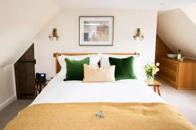 a bedroom with a large bed with green pillows at The Red Lion in East Bergholt