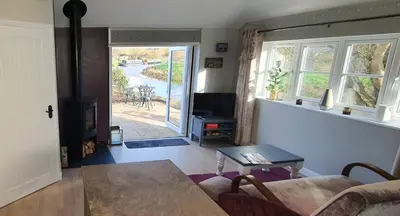 a living room with a couch and a table and a tv at River Cottage in Stoke Ferry