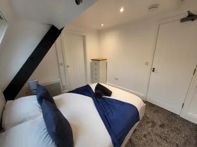 a bedroom with a large bed with blue pillows at City Centre Wallgate Apartments- Step back into Roman history in Colchester