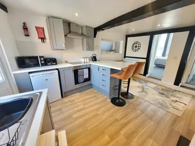 a kitchen with white counters and a table in it at City Centre Wallgate Apartments- Step back into Roman history in Colchester