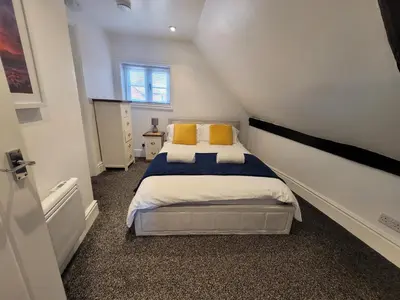 a small bedroom with a bed with yellow pillows at City Centre Wallgate Apartments- Step back into Roman history in Colchester