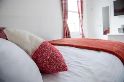 a bedroom with red and white pillows on a bed at Trinity, Central Cambridge Flat in Cambridge