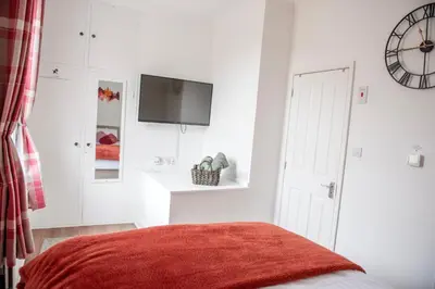a white bedroom with a bed and a flat screen tv at Trinity, Central Cambridge Flat in Cambridge