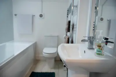 a white bathroom with a sink and a toilet at Trinity, Central Cambridge Flat in Cambridge