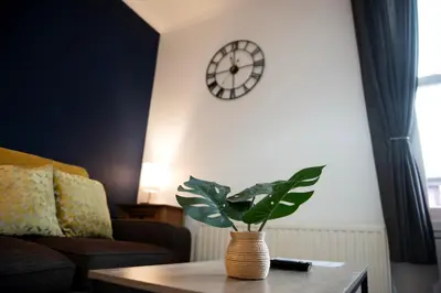 a living room with a table and a clock on the wall at Trinity, Central Cambridge Flat in Cambridge