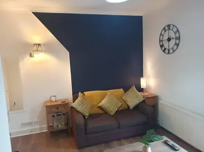 a living room with a couch and a clock on the wall at Trinity, Central Cambridge Flat in Cambridge