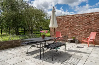 a patio with a table and chairs and an umbrella at Contemporary Barn Harleston Norfolk in Harleston