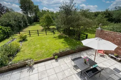 an outdoor patio with an umbrella and a lawn at Contemporary Barn Harleston Norfolk in Harleston