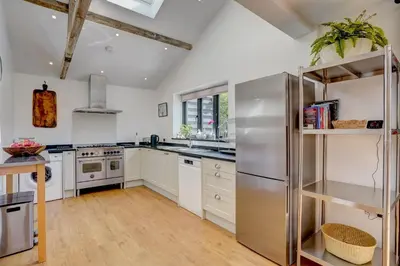 a kitchen with white cabinets and a stainless steel refrigerator at Contemporary Barn Harleston Norfolk in Harleston