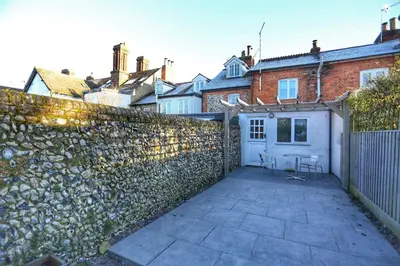 a backyard with a stone wall and a table and chairs at Cottage, Central Saffron Walden, Garden, Little Braybrooke in Saffron Walden