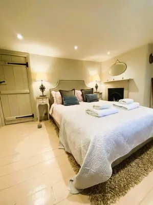 a bedroom with a large bed and a fireplace at Beautiful Immaculate Aldeburgh cottage, free parking, sunny outdoor space, dog friendly - perfect for Spring seaside escapes in Aldeburgh