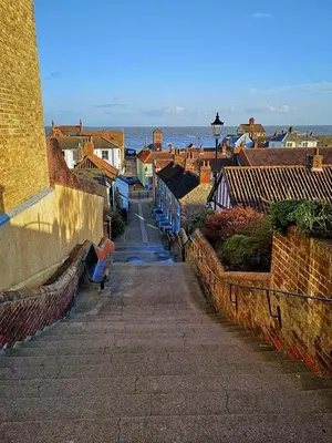 a city street with buildings and the ocean in the background at Beautiful Immaculate Aldeburgh cottage, free parking, sunny outdoor space, dog friendly - perfect for Spring seaside escapes in Aldeburgh