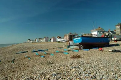 a blue boat sitting on a rocky beach at Beautiful Immaculate Aldeburgh cottage, free parking, sunny outdoor space, dog friendly - perfect for Spring seaside escapes in Aldeburgh