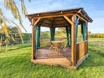 a wooden gazebo with a table and chairs at Lion House- Uk45705 in Brinkley