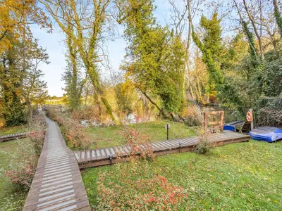 a wooden walkway in a park with trees and a field at Lion House- Uk45705 in Brinkley