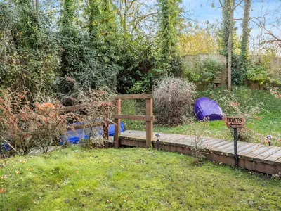 a garden with a wooden bridge and a sign that says pray at Bear House- Uk45704 in Brinkley