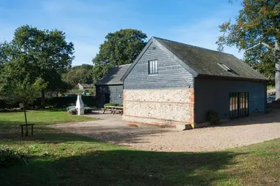 a barn with a picnic table in front of it at Marshlands House, Sleeps 16 - Country barn with hot tub in Woodbridge