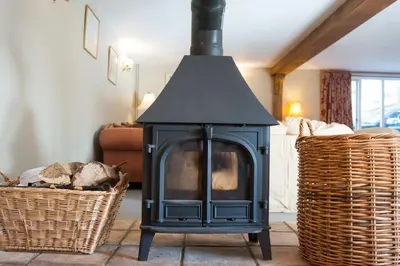 a black fireplace in a living room with two baskets at Marshlands House, Sleeps 16 - Country barn with hot tub in Woodbridge