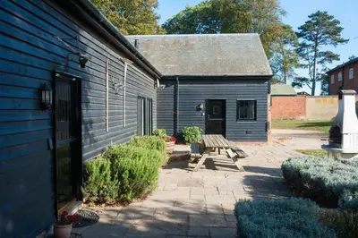 a blue building with a picnic table and a bench at Marshlands House, Sleeps 16 - Country barn with hot tub in Woodbridge