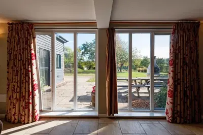 an empty room with sliding glass doors looking out onto a patio at Marshlands House, Sleeps 16 - Country barn with hot tub in Woodbridge