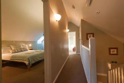 a bedroom with a bed and a hallway with a staircase at Marshlands House, Sleeps 16 - Country barn with hot tub in Woodbridge