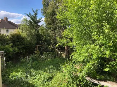 a yard with trees and bushes and a house at Bright & spacious first floor apartment Cambridge in Chesterton