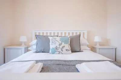 a bedroom with a white bed with pillows and two lamps at 1 & 2 Abbey Mews, Leiston in Leiston