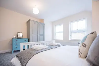 a bedroom with a white bed and a blue dresser at 1 & 2 Abbey Mews, Leiston in Leiston