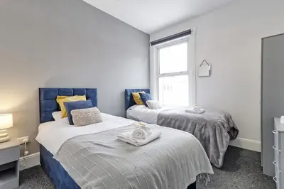 two beds in a room with a window at Beautiful Spacious four bedroom house with parking for 2 cars, 5 minute walk to southend station in Southend-on-Sea