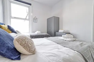 a white bedroom with two beds and a window at Beautiful Spacious four bedroom house with parking for 2 cars, 5 minute walk to southend station in Southend-on-Sea