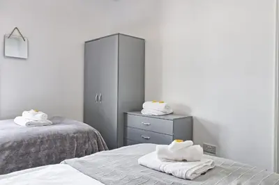 a bedroom with two beds and a dresser with towels at Beautiful Spacious four bedroom house with parking for 2 cars, 5 minute walk to southend station in Southend-on-Sea