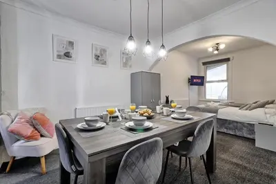 a living room with a dining room table with chairs at Beautiful Spacious four bedroom house with parking for 2 cars, 5 minute walk to southend station in Southend-on-Sea