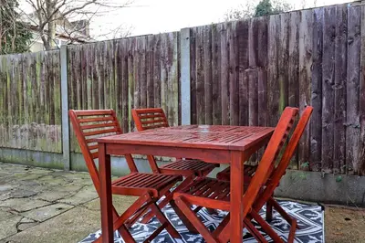 a wooden table with four chairs and a fence at Beautiful Spacious four bedroom house with parking for 2 cars, 5 minute walk to southend station in Southend-on-Sea